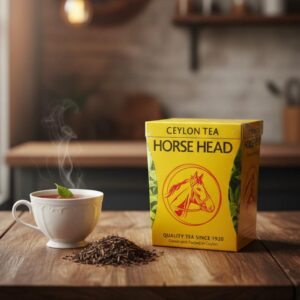 caja amarilla Té de Ceylán Horse Head, calidad premium desde 1920, té negro hojas sueltas en mesa, taza de té humeante con hoja de menta