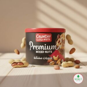Envase cilíndrico negro con tapa roja de frutos secos mixtos Crunchy Nuts Premium. Frutos secos y maní dispersos sobre una mesa de madera clara.