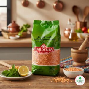 Empaque verde de Lentejas Rojas Peladas marca Gardenia Grain d’Or de 907 gramos, sobre una mesa de madera rústica junto a un limón fresco, hojas de menta y un cuenco con lentejas secas en un ambiente de cocina cálido.