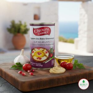 Lata de Baba Ghannouge (crema de berenjena) Chtoura Garden sobre tabla de madera, con fondo de terraza mediterránea, decorada con granada, ajo y aceite de oliva.