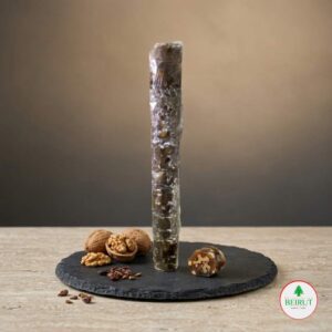 Dulce artesanal Sujuk de Nuez sobre plato de pizarra negra, rodeado de nueces enteras y troceadas, con fondo neutro para tienda gourmet Beirut Market.