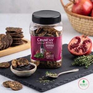 Tarro de galletas Crunchy Bites sabor tomillo y granada, junto a una granada abierta y un bowl con melaza