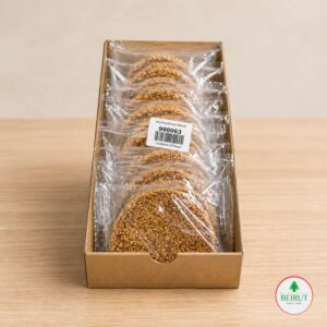 Caja de cartón con 10 galletas redondas de ajonjolí artesanal empacadas individualmente sobre fondo de madera clara.